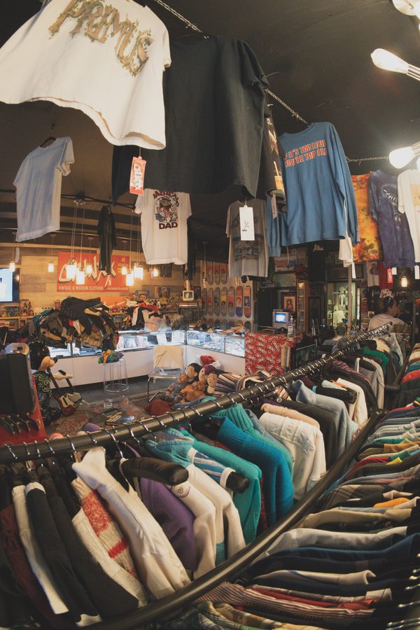 Inside Chunxx Treasures: vintage tees hanging from the ceiling over packed racks, the CHUNXX sign and glass counter in back